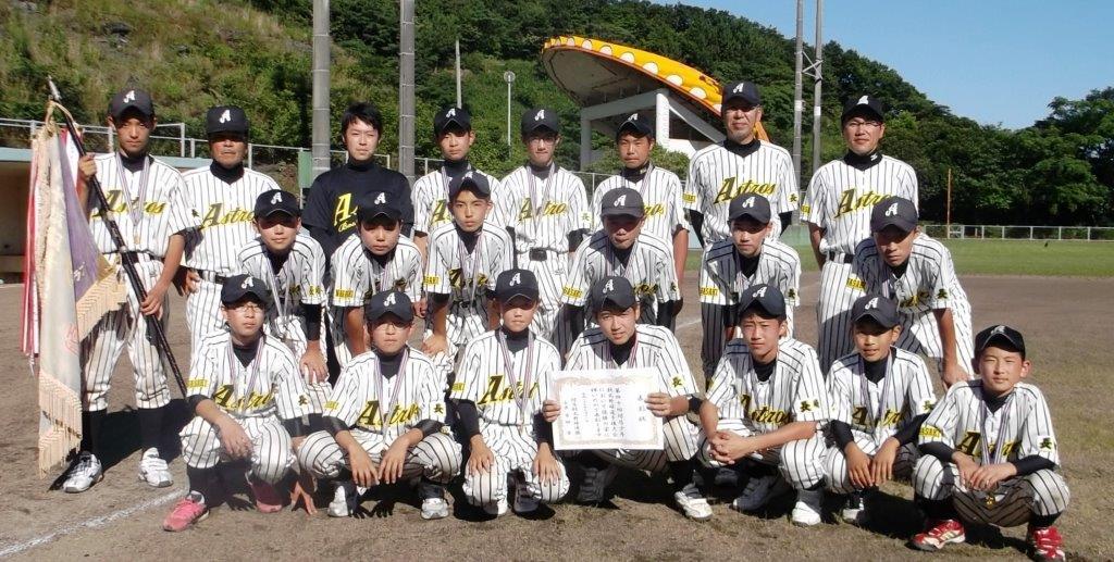 優勝旗と賞状を持ち正面を向く優勝チーム(美津島アストロクラブ)メンバーの写真