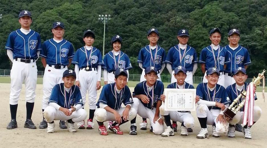 賞状とトロフィーを手に正面を向く優勝チーム(対馬TKマックス)メンバーの写真