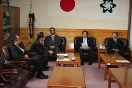 市長室で椅子に座って話し合う加留部委員長と財部市長の写真