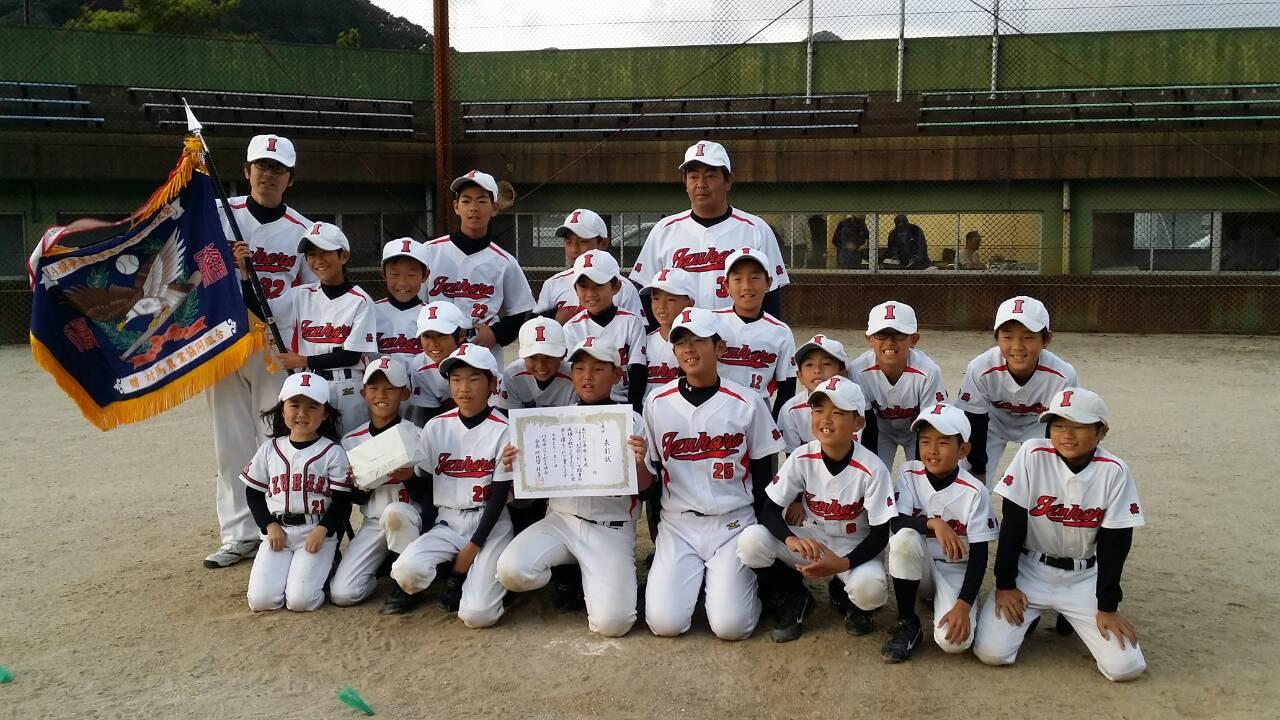 優勝旗と賞状を持ち正面を向く優勝チーム（厳原少年クラブ）メンバーの写真