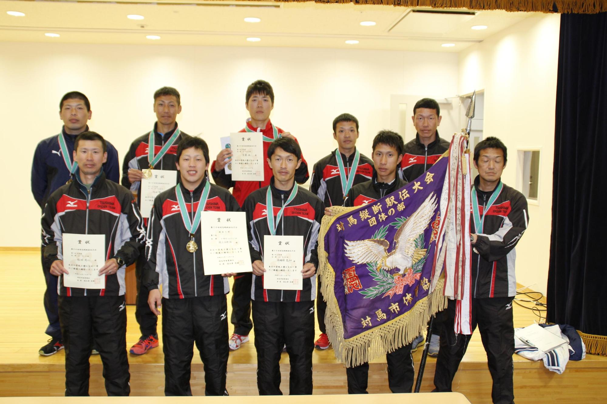 優勝旗と賞状を手に正面を向く団体の部で優勝した陸上自衛隊チームメンバーの写真