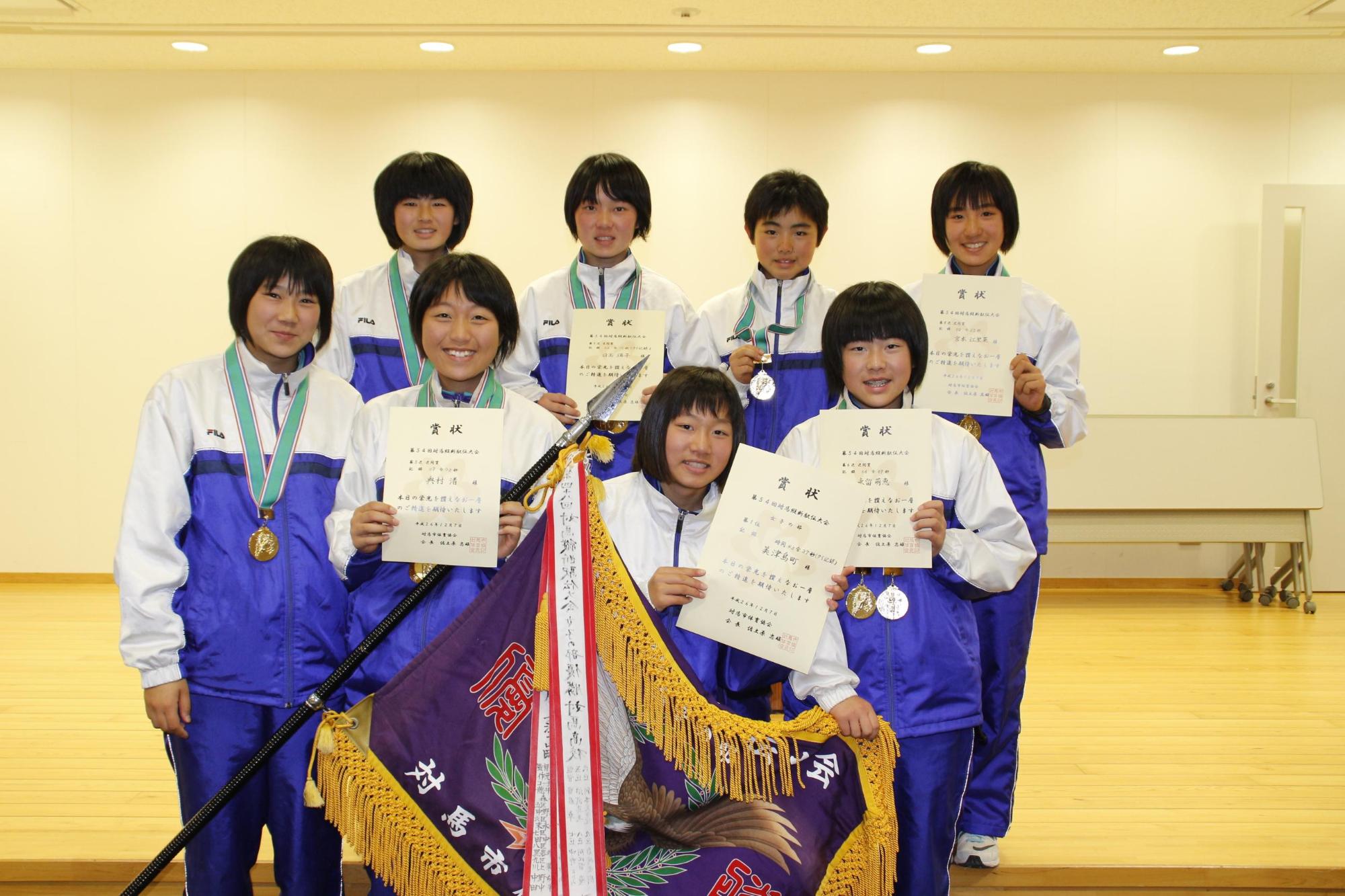 優勝旗と賞状を手に正面を向く女子の部で優勝した美津島チームメンバーの写真