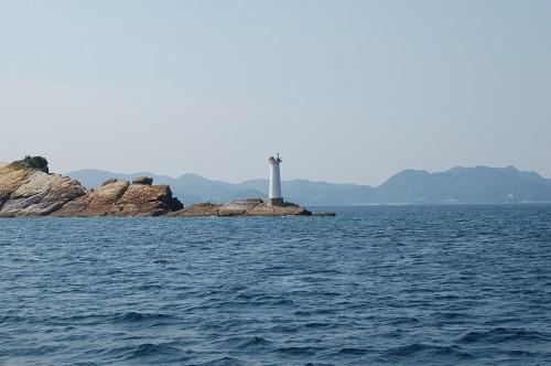 海の中の岩場に建つ白い芋崎灯台の写真