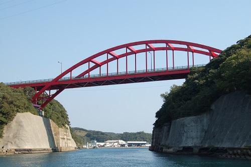 青い空の下に運河の上に架かる赤い万関橋の写真