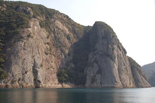 水面からかなりの高さのある断崖絶壁の巨大な鋸割岩の写真