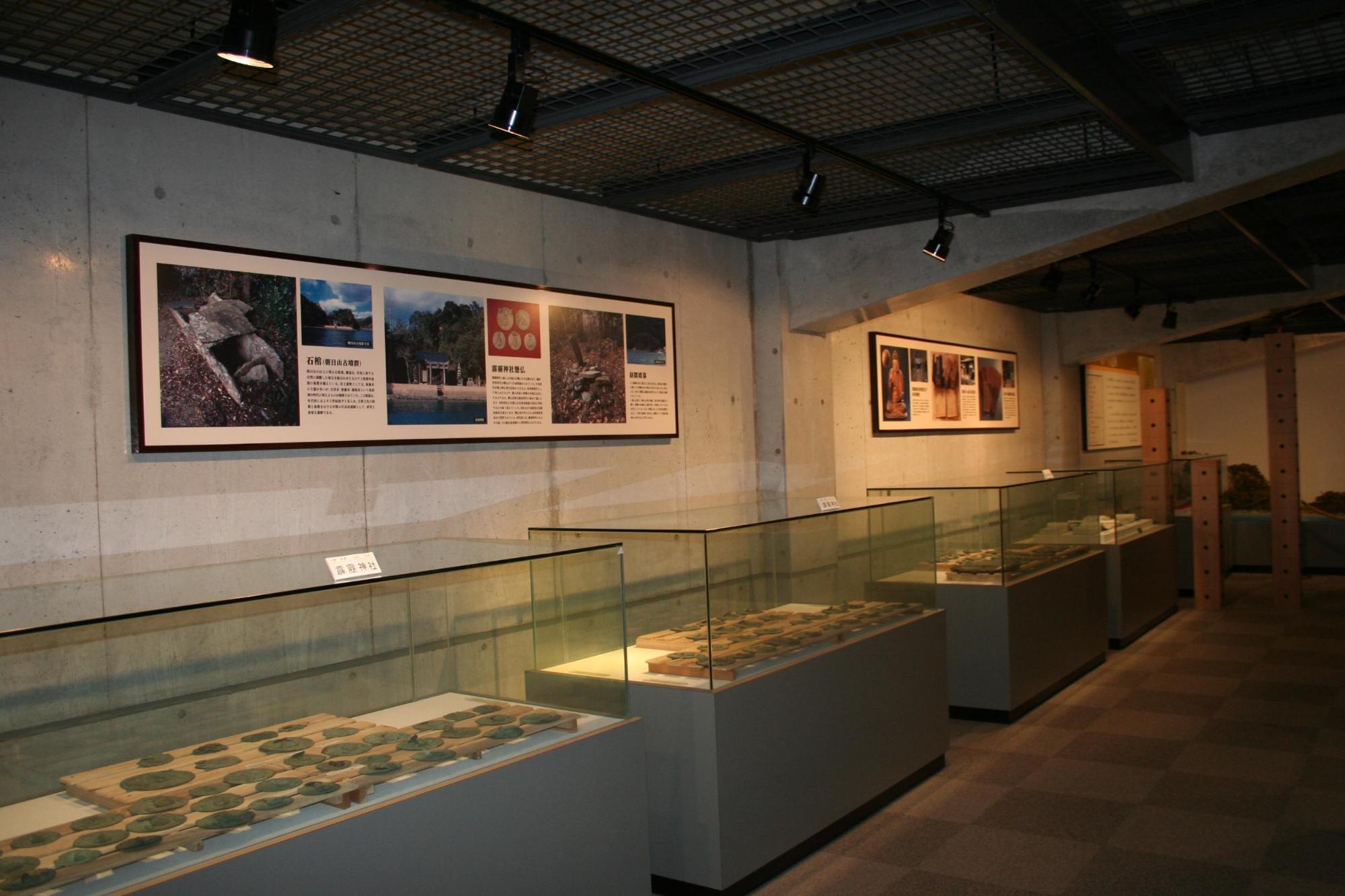 ショーケースに並ぶ展示品と壁に貼られた民族資料のパネルの写真
